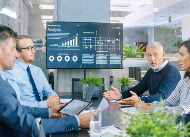 Colleagues having meeting in front of screen with data dashboard