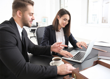 Two colleagues discussing in front of laptop screen