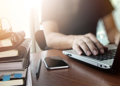 Person working on laptop next to mobile phone