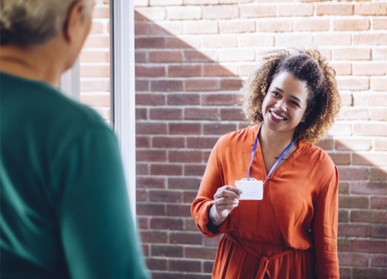 Social worker showing ID badge to resident at front door